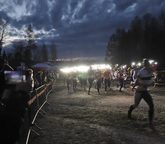 Starten på Tiomilakavlen i Ånnaboda 2022. Förstasträckslöparna rusar fram med sina pannlampor.
