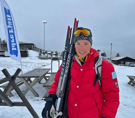 Tove Alexandersson med ett leende och två par skidor mot axeln på Idrefjäll.