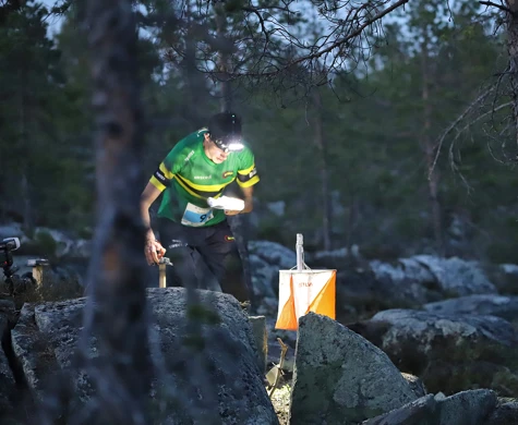 NTNUI-löpare stämplar vid en kontroll i mörkret på Tiomila i Skellefteå 2023.