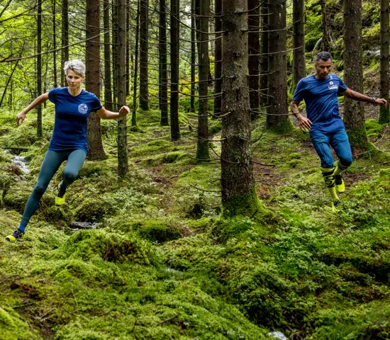 Två löpare med Icebug-skor springer i skogen.