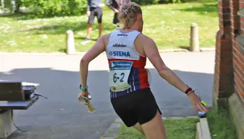 En tjej stämplar vid en kontroll intill en tegelvägg på sprint-SM-stafetten i Lund.