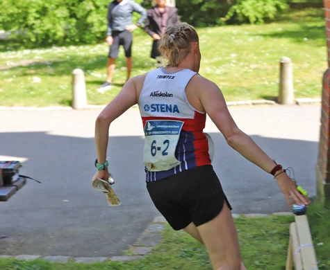 En tjej stämplar vid en kontroll intill en tegelvägg på sprint-SM-stafetten i Lund.